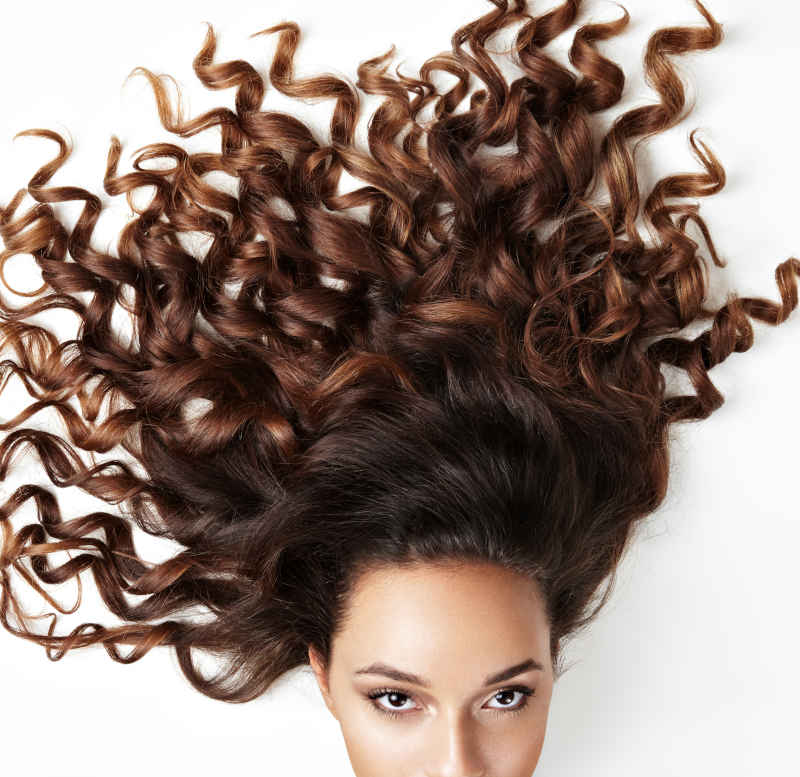 Woman with curly brown hair spread out on a white background.