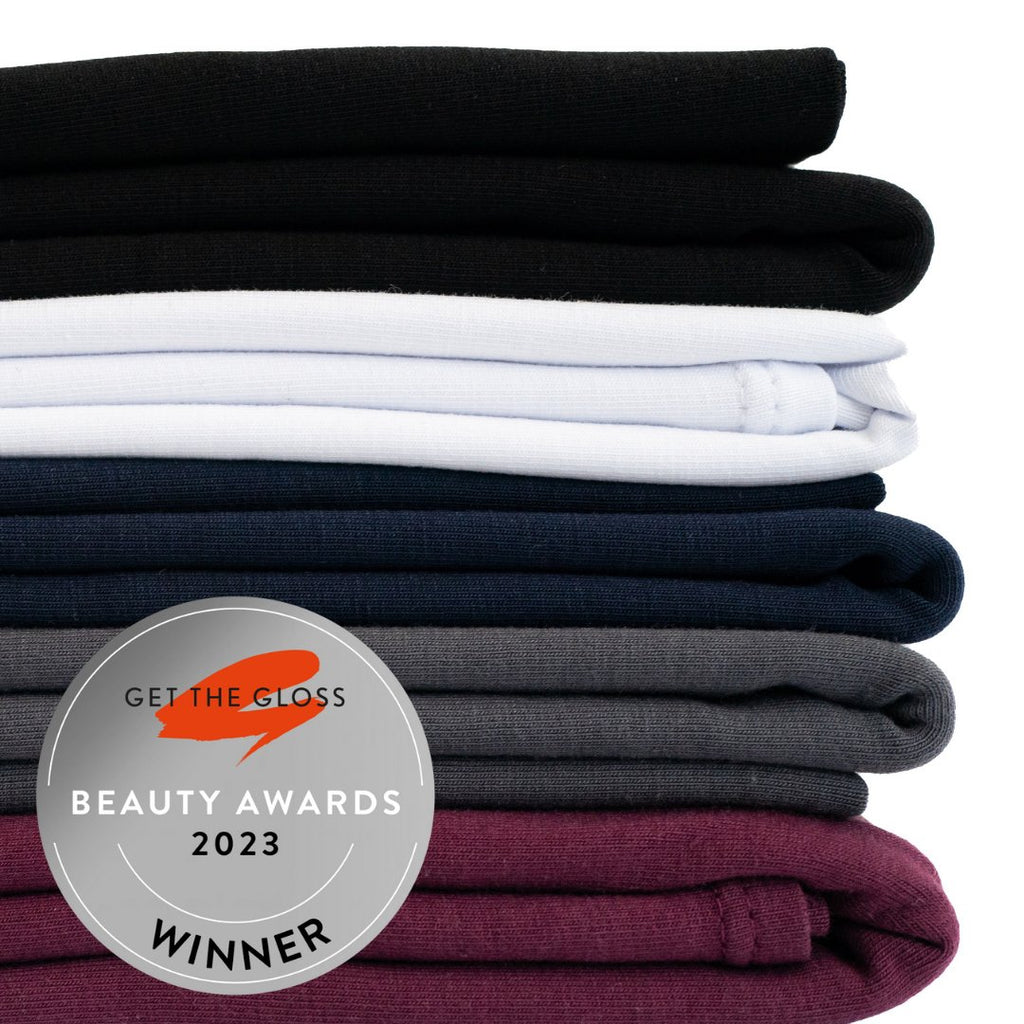 Stack of neatly folded The Classics jersey cotton clothing in various shades with a 'get the gloss beauty awards 2023 winner' badge by Good Wash Day.
