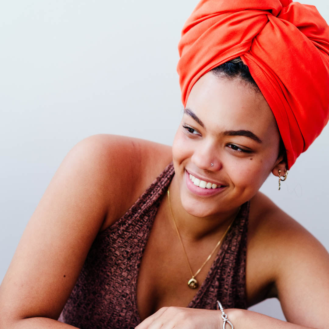 Woman with hair wrapped in an organic jersey cotton hair towel in bright orange - Good Wash Day