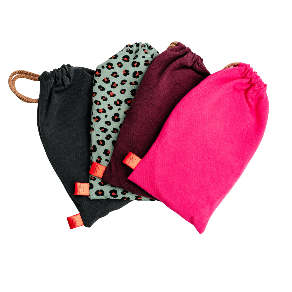 The Good Wash Day set includes four eco-friendly drawstring fabric bags in black, leopard print, maroon, and bright pink. Each bag has a small red tag and is perfect for carrying reusable face cloths or other essentials with style.