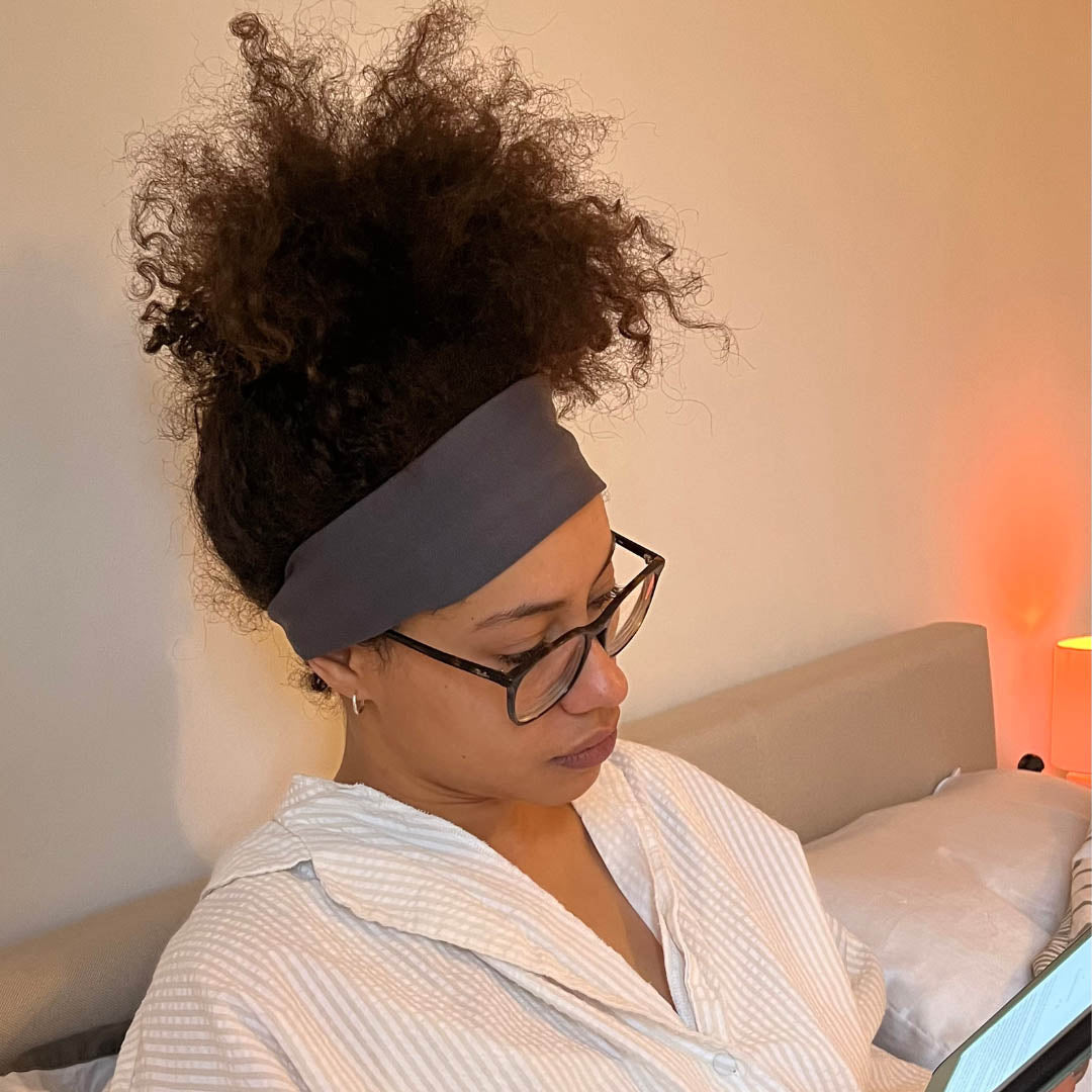 Woman with afro hair reading in bed whilst wearing dark grey jersey cotton headband – Good Wash Day