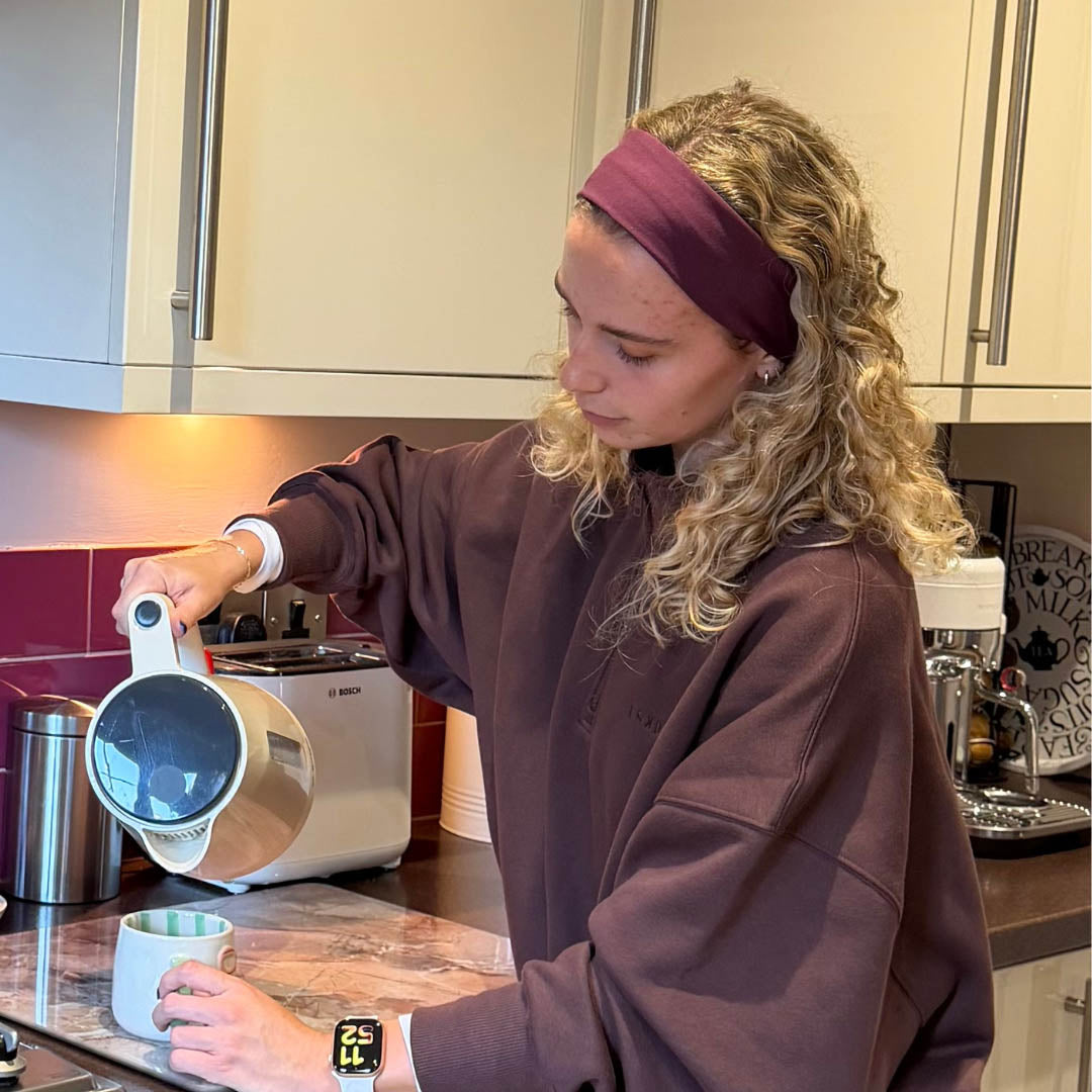 Woman wearing mulberry organic jersey cotton headband making a cup of tea - Good Wash Day