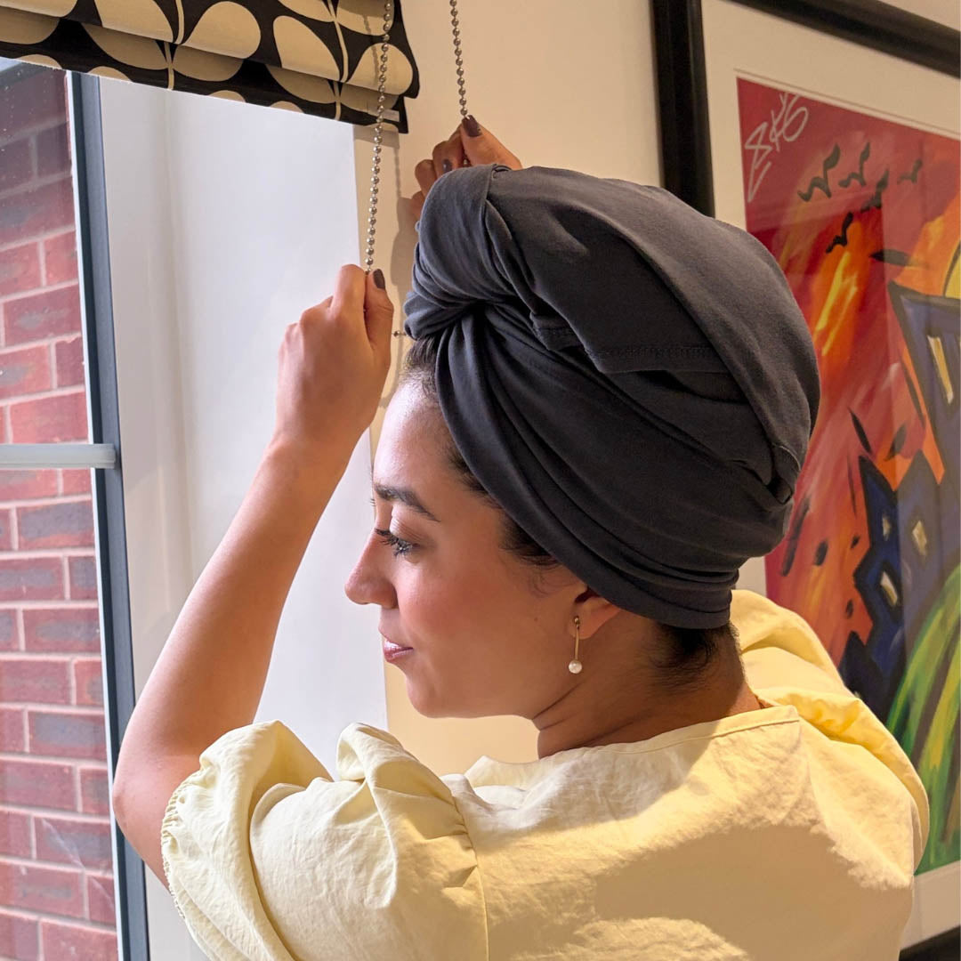 Woman wearing grey organic jersey cotton hair plopping towel whilst adjusting window blinds – Good Wash Day