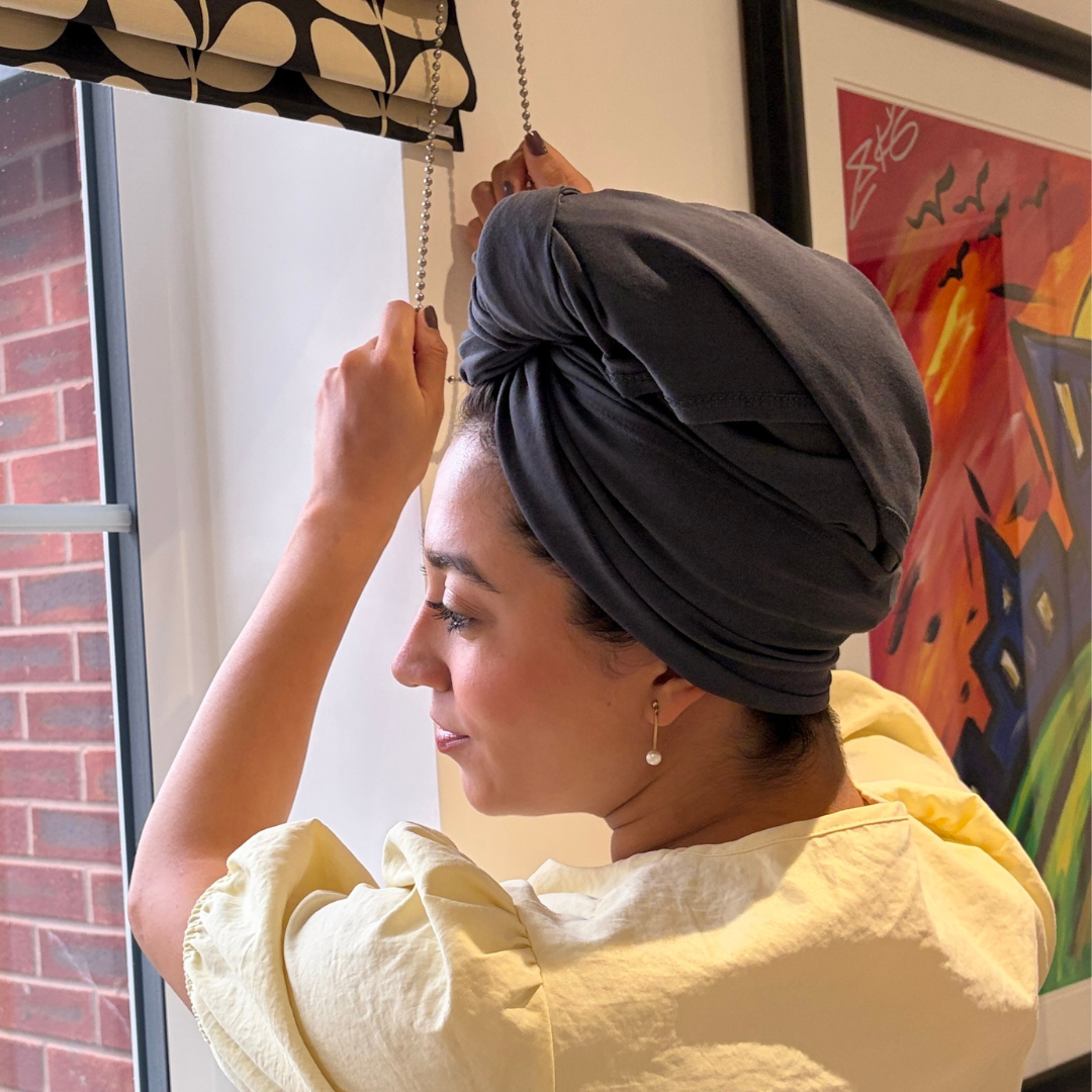 Woman wearing grey organic jersey cotton hair plopping towel whilst adjusting window blinds – Good Wash Day