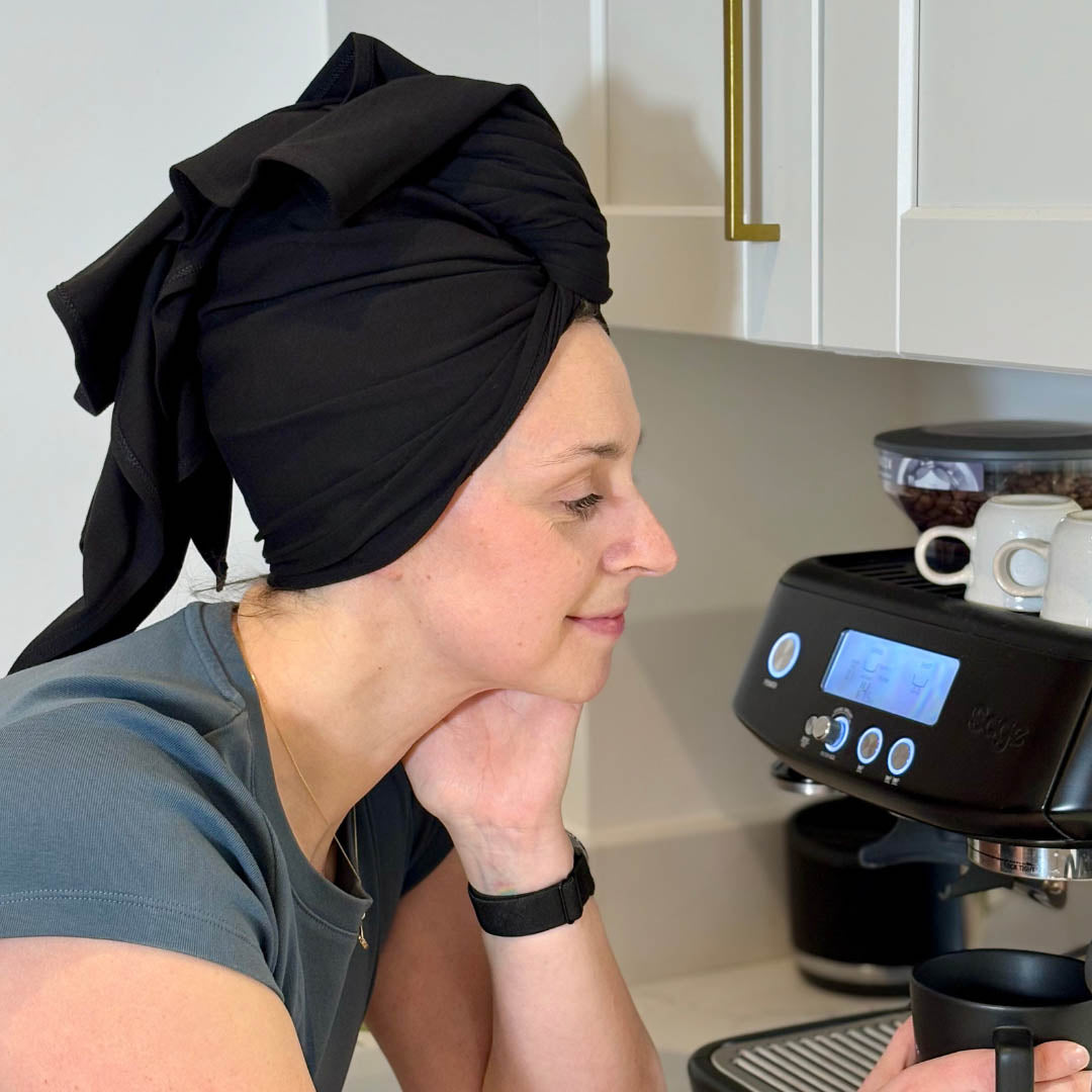 Woman making coffee with hair wrapped in black XL organic jersey cotton hair towel wrap – Good Wash Day