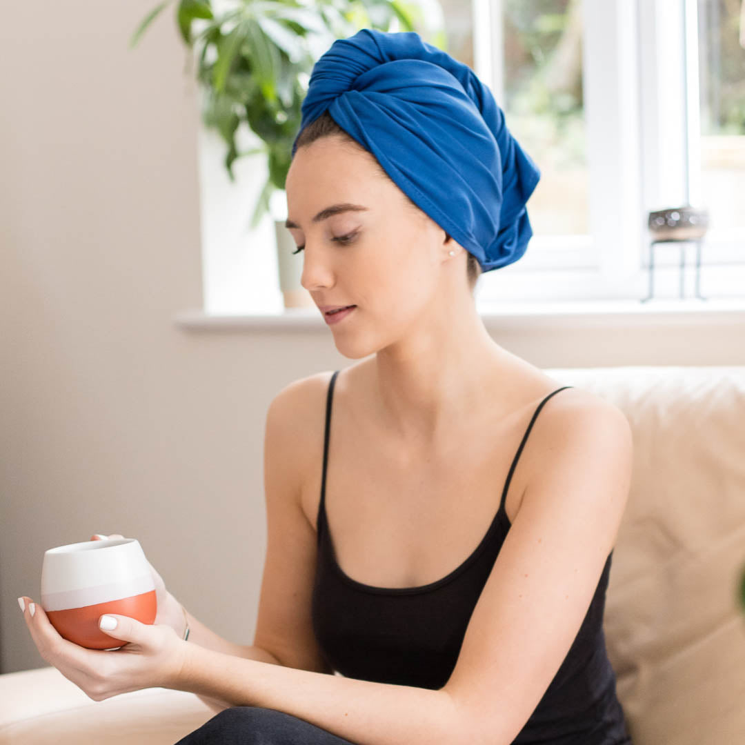 Woman in kitchen relaxing whilst wearing cobalt blue XL organic jersey cotton hair towel wrap – Good Wash Day