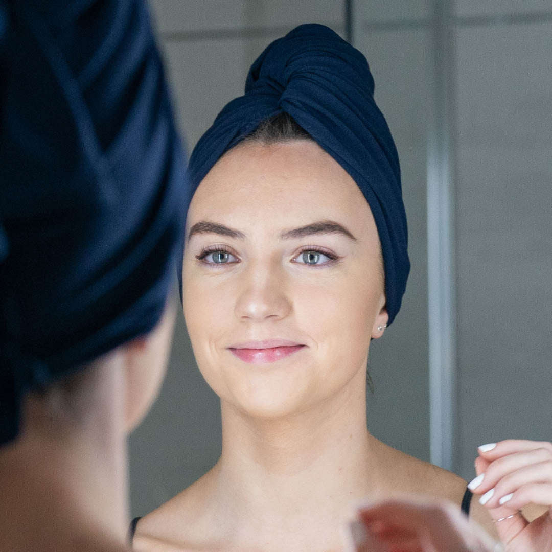 Woman with long hair wearing navy XL organic jersey cotton hair towel wrap in her bathroom – Good Wash Day