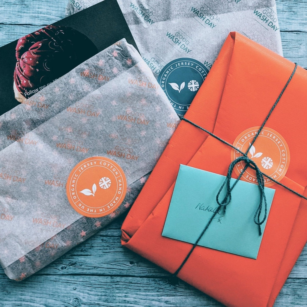 A neatly ordered Wrapped wrapped in orange paper with a blue note attached, accompanied by cards on a wooden surface.