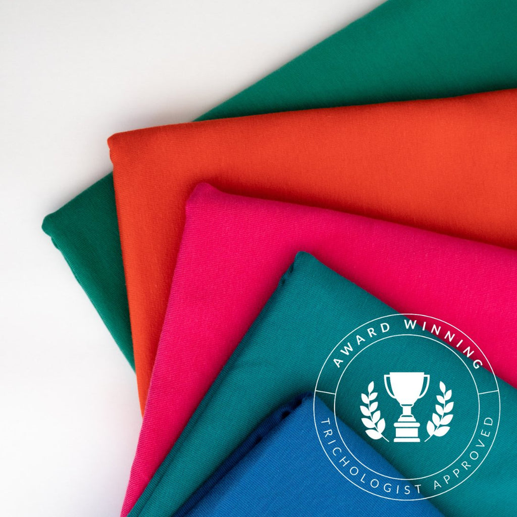 Four neatly folded colorful, handmade fabrics with The Jewels by Good Wash Day badge displayed on one.