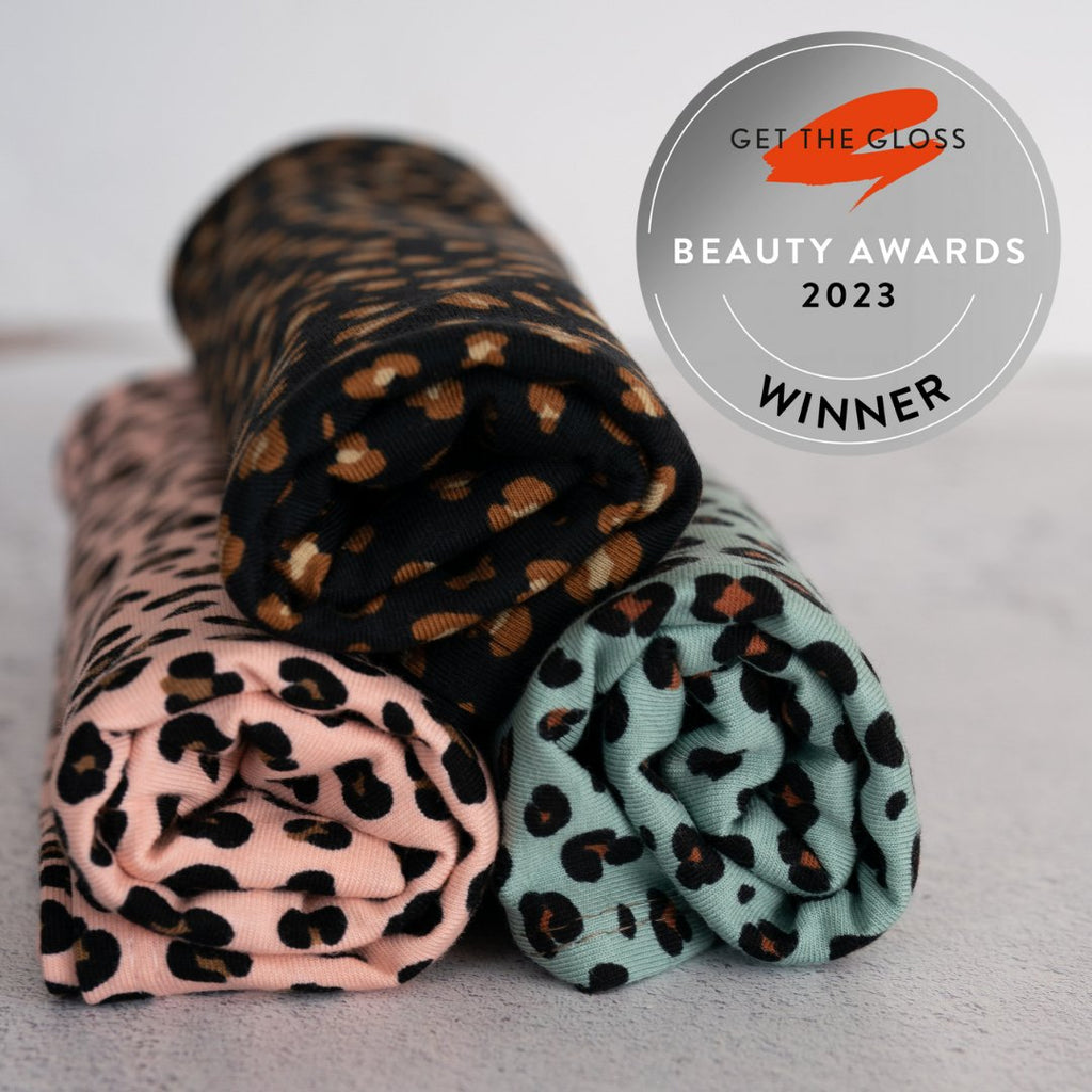 Three rolled-up Good Wash Day Leopard Prints organic cotton towels with leopard print patterns, featuring a seal indicating an award from 'get the gloss beauty awards 2023.'